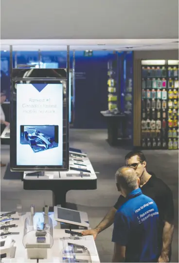  ?? Brent Lewin / Bloombe rg Files ?? Customers browse mobile phones at a Bell Canada store. Bell and rival Telus have both pulled their guidance for 2020, citing a lack of clarity due to the COVID-19 pandemic.