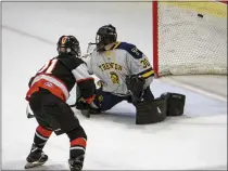  ?? TIMOTHY ARRICK — MEDIANEWS GROUP PHOTO ?? Brett Harris of Brother Rice flips the puck past Trenton’s Luc Miklos as the Warriors defeat the Trojans 4-2in the MHSAA Division 2 semifinals Thursday at USA Hockey Arena in Plymouth.