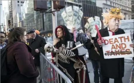  ?? ASSOCIATED PRESS ?? A member New York City Mayor Bill de Blasio’s Community Affairs Unit, left, tells demonstrat­ors they can’t enter a Tuesday rally in opposition to the Republican tax plan outside Trump Tower because they are wearing masks and carrying signs in New York.