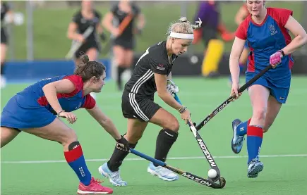  ?? MURRAY WILSON/STUFF ?? College’s Michaela Curtis, centre, weaves her way though the High School Hockey Club defence during their clash at the twin turfs.