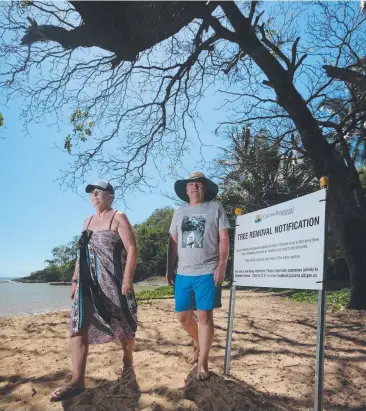  ??  ?? ANGRY: Trinity Beach residents Jean and David Morgan walk past the dead trees. Picture: STEWART McLEAN