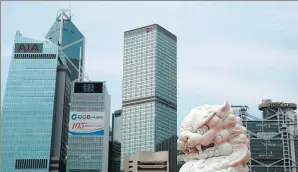  ?? BOBBY YIP / REUTERS ?? A stone lion stands guard over office towers in Central, Hong Kong’s main financial district.