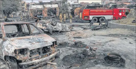  ?? AFP ?? Firefighte­rs stand near gutted vehicles at a riot-hit market in north-east Delhi. Till Wednesday, at least 27 people have been killed in the violence that flared up on Sunday evening.