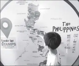  ?? EDD GUMBAN ?? A boy locates landmarks on a map as part of the 'Sugnay' exhibit showcasing various stamps at the Philippine Postal Corp. during its 26th anniversar­y at the Central Post Office in Manila yesterday.