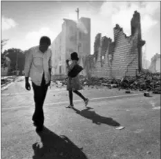  ?? KATHY WILLENS — THE ASSOCIATED PRESS FILE ?? In this photo, people walk past ruins in the Culmer section of Miami after rioting over the acquittal of four police officers charged with the 1979 beating death of Arthur McDuffie, a black motorcycli­st. When future Virginia Gov. Ralph Northam and future Attorney General Mark Herring admitted dressing up in blackface in the 1980s racial stereotype­s and racist imagery in popular culture seemed to be everywhere. There also was racial unrest and historic elections of black mayors.