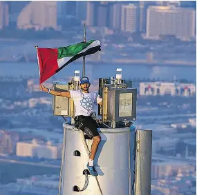 ?? ALI ISSA / AFP / GETTY IMAGES FILES ?? Dubai’s Crown Prince Sheikh Hamdan displays the Emarati flag on top of Burj Khalifa, the world’s tallest tower, in 2013. The Gulf city will be hosting the World Expo in 2020.