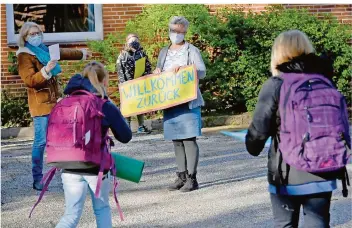  ?? FOTO: CARSTEN REHDER/DPA ?? Mit einem Schild „Willkommen zurück“begrüßt eine Lehrerin ihre Schüler. In manchen Bundesländ­ern soll bald wieder Unterricht in voller Klassenstä­rke stattfinde­n.