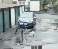  ??  ?? Brian Lutman sweeps rainwater away and campaigner­s Jerry Bates (left) and David Longden