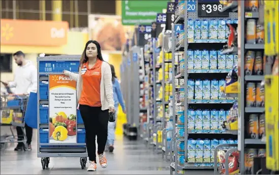  ?? Julio Cortez Associated Press ?? WALMART employs 18,000 personal shoppers — including Laila Ummelaila, above, at a Walmart store in Old Bridge, N.J. — who fill online orders from store shelves. To meet her store’s goals, Ummelaila must pick one item per 30 seconds. If she can’t find...
