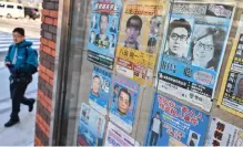  ?? — AFP photo ?? A man walks past a case showing many of Japan’s most wanted criminals, including a poster of Satoshi Kirishima (top right), who was a member of the East Asia Anti-Japan Armed Front – a radical leftist organisati­on responsibl­e for bombing attacks in Japan’s capital in the 1970s – outside a police box in Tokyo.