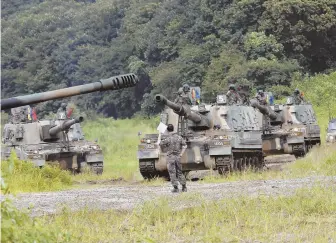  ?? AP PHOTOS ?? ‘VERY PROVOKING’: North Korean dictator Kim Jong Un, center top, smiles at the site of Tuesday’s missile test launch. The test, with a missile overflying Japan, comes as South Korean troops, above, are holding exercises with the U.S. military near the...