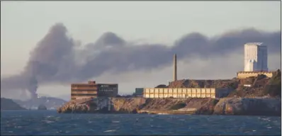  ??  ?? ALCATRAZ: Smoke pours from a fire at the Chevron Richmond Refinery, seen behind Alcatraz Island in San Francisco, Monday. Officials have told residents of two Northern California cities to shelter- in- place as a fire at the refinery releases plumes of...