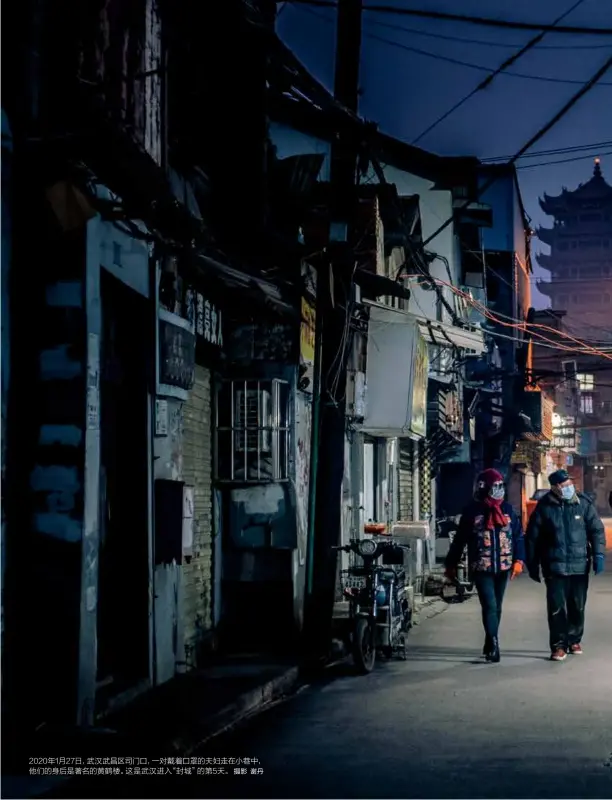  ?? 摄影 谢丹 ?? 2020年1月27日，武汉武昌区司门口，一对戴着口罩的夫妇走­在小巷中，他们的身后是著名的黄­鹤楼。这是武汉进入“封城”的第5天。
