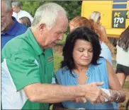  ?? Jeremy stewart ?? Tommy Sanders (left) gives former Pizza Farm employee Jan Gore a jar of the restaurant’s original salad dressing during the groundbrea­king for the new Pizza Farm on Aug. 2.