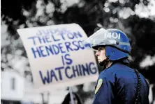  ?? Noah Berger / Special to The Chronicle 2011 ?? A police officer at Occupy Oakland in 2011 is next to a sign referring to the U.S. judge monitoring Oakland police reforms.