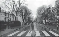  ?? AKIRA SUEMORI/ THE ASSOCIATED PRESS FILES ?? A man walks on the crossing made famous from the album cover of The Beatles’ Abbey Road in front of Abbey Road Studios, seen at left, in London.