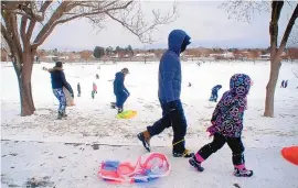  ?? ADOLPHE PIERRE-LOUIS/JOURNAL ?? Braving the frigid air, hundreds headed to Santa Fe Village Park near Unser and Montaño NW to sled and play in Sunday’s snow.
