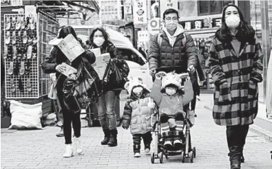  ?? AHN YOUNG-JOON/AP ?? People wear face masks at a shopping district in Seoul, South Korea. Mask-wearing is the new normal in China and other spots in Asia.