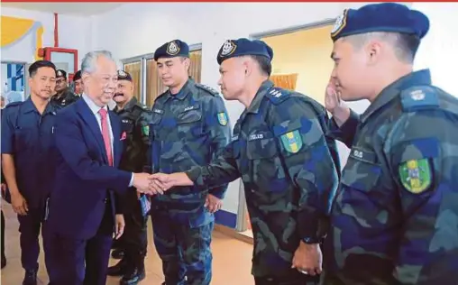  ?? PIC BY MOHD YUSNI ARIFFIN ?? Home Minister Tan Sri Muhyiddin Yassin greeting army officers during a visit to the General Operations Force 4th Battalion Complex in Semenyih yesterday.