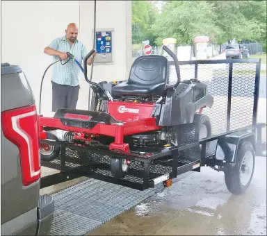  ?? Westside Eagle Observer/SUSAN HOLLAND ?? Gravette businessma­n Ricky Sehgal washes his zero turn mower in one of the manual car wash bays at the Gravette Auto Wasche on Highway 59 S. Sehgal was one of the first week’s customers after the business opened on Friday, July 3. Levi Duncan is manager of the car wash, owned by the John Lykins family.