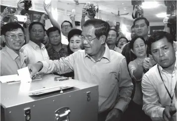  ?? Associated Press ?? ■ Cambodian Prime Minister Hun Sen, center, of the Cambodian People’s Party casts his ballot Sunday in the country’s general election at a polling station in Takhmua in Kandal province, southeast of Phnom Penh, Cambodia. Cambodians have begun voting in...