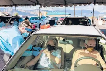  ?? ALEX WELSH/THE NEW YORK TIMES ?? Herminia Sharp, left, and Dennis Sharp receive COVID-19 vaccines at a vaccinatio­n center Friday in Lake Elsinore, California. With the pandemic raging, vaccines are suddenly in short supply nationwide.