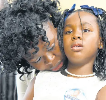  ??  ?? Japhene Campbell comforts her daughter, Seraphine Bair, during the funeral for Benjamin Bair at the North Street Seventh-day Adventist Church in Kingston yesterday.