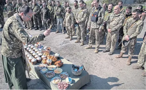  ?? ?? A military Orthodox priest blesses traditiona­l food during the Easter celebratio­n with Ukraine’s 128 brigade.