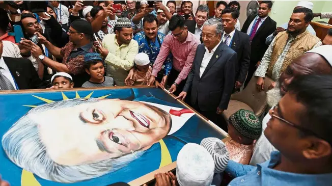  ??  ?? Picture perfect: Dr Mahathir receiving a token of appreciati­on from the Muslim community during his visit to the Hohola Mosque after attending the Apec summit in Papua New Guinea. –Bernama