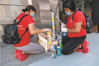  ?? Photos by Nick Otto / Special to The Chronicle ?? Sanitation company BerryClean employees Jackie Mendez and Doris Chun prepare their supplies before cleaning a San Francisco building. They wear singleuse protective equipment.