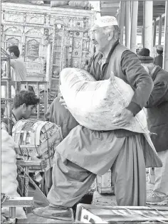  ??  ?? Shiite Hazara minority traders load fruit and vegetables at a market before returning to their heavily guarded enclave where they live on the outskirts of Quetta. — AFP photos