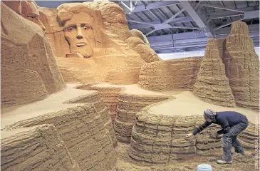  ??  ?? Leonardo Ugolini works on a sculpture inspired by Mount Rushmore’s four presidents.