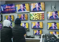  ?? (Yonatan Sindel/Flash90) ?? PEOPLE WATCH television screens in an electric appliance shop on Tuesday in Jerusalem, showing US President Donald Trump as he unveils his peace plan.