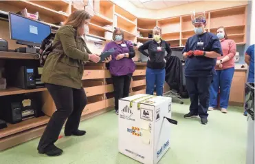  ?? UW HEALTH ?? Officials at UW Health in Madison ensure a box carrying the COVID-19 vaccine is intact on Monday. UW Health received its initial shipment of 3,900 doses on the first day it was available.