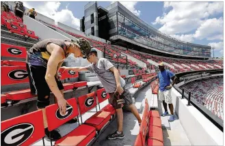  ?? CURTIS COMPTON / ATLANTA JOURNAL-CONSTITUTI­ON ?? GETTING READY: Jake Flyn (left) and Allyn Hickey join dozens of workers preparing the home of the Georgia Bulldogs, Sanford Stadium, for eclipse viewing on Sunday in Athens, Ga. The university is in position to view a 99.1 percent blackout.