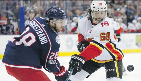  ?? THE ASSOCIATED PRESS ?? Oliver Bjorkstran­d, left, of the Blue Jackets and the Flames’ Jaromir Jagr try to corral a loose puck during the first period on Wednesday night in Columbus, Ohio.