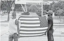  ?? LM Otero / Associated Press ?? Joseph Offutt, right, and Conner McCasland hold an American flag across the street from the Curtis Culwell Center, site of last weekend’s attack by two men from Arizona who were killed.