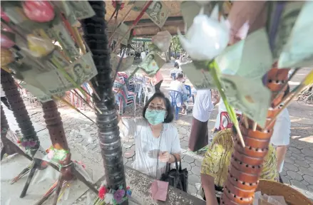  ?? CHANAT KATANYU ?? A woman wearing a face mask to protect her from Covid-19 makes merit at a temple earlier this month.