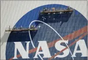  ?? JOHN RAOUX — THE ASSOCIATED PRESS ?? Workers near the top of the 526ft. Vehicle Assembly Building at the Kennedy Space Center spruce up the NASA logo standing on scaffolds May 20 in Cape Canaveral, Fla.