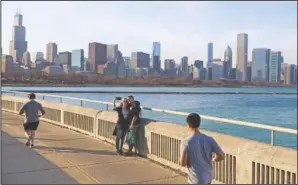  ??  ?? A couple poses for a selfie March 9 as joggers pass by along Lake Michigan at Lakefront Trail in Chicago.
(File Photo/AP/Shafkat Anowar)