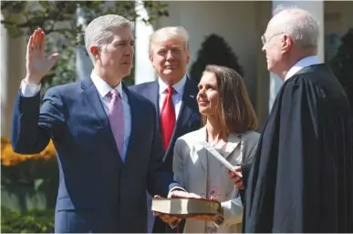  ?? ASSOCIATED PRESS PHOTOS ?? President Donald Trump watches as Supreme Court Justice Anthony Kennedy administer­s the judicial oath to Justice Neil Gorsuch, accompanie­d by his wife, Marie Louise, during a swearing-in ceremony Monday at the White House in Washington.