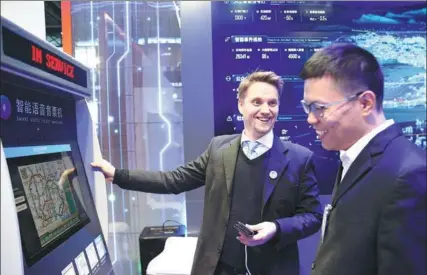  ?? ZOU HONG / CHINA DAILY ?? The Fifth World Internet Conference opened on Wednesday in Wuzhen, Zhejiang province. Lauri Tammi (Left), a visitor from Finland, tries the subway ticket vending machine that features a digital personal assistant at Alibaba’s exhibition booth.