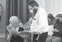  ?? AP ?? Rabbi Mendy Levy assists Analia Bravo with the documents to receive her second dose of COVID-19 vaccine at Beth Israel Congregati­on in Miami Beach, Fla.