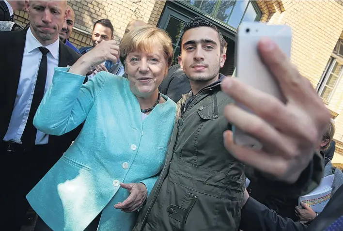  ?? GETTY ?? Angela Merkel denies that this ‘selfie’ with a migrant, taken at a shelter outside Berlin, has been encouragin­g ‘hundreds of thousands of people to leave their homes and embark on this difficult road’