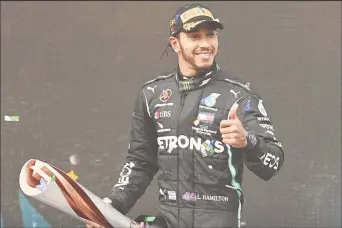  ??  ?? Mercedes’ Lewis Hamilton celebrates on the podium with a trophy after winning the race and the world championsh­ip Pool via REUTERS/Ozan Kose