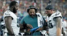  ?? MARY SCHWALM — THE ASSOCIATED PRESS FILE ?? Philadelph­ia Eagles defensive line coach Chris Wilson, center, confers on the sideline with defensive ends Fletcher Cox, left, and Chris Long, right, during a game against the New England Patriots in Foxborough, Mass. The Eagles have so much depth on their defensive line they rotate seven players and keep them fresh for the fourth quarter.