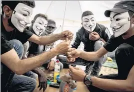  ??  ?? PALESTINIA­NS wearing masks to hide their identities last week prepare a piece for a kite at the Bureij refugee camp near Deir al Balah in the Gaza Strip.