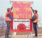  ?? FOTO: DPA ?? Zwei Mitarbeite­r des Baukonzern­s Philipp Holzmann stellen 1999 in Oberhausen ein DankesSchi­ld auf, nachdem Kanzler Gerhard Schröder das Unternehme­n zunächst rettete.