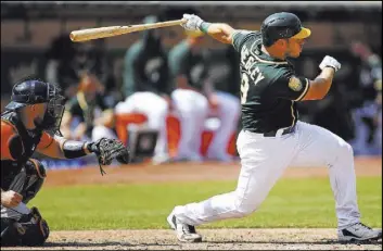  ?? Ben Margot The Associated Press ?? Josh Phegley follows through on the first of his two run-scoring doubles Saturday in front of Astros catcher Max Stassi in the sixth inning of the Athletics’ 7-1 win.