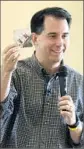  ??  ?? IN IOWA, ScottWalke­r shows off a photo of himself as a boy holding the Iowa state flag.